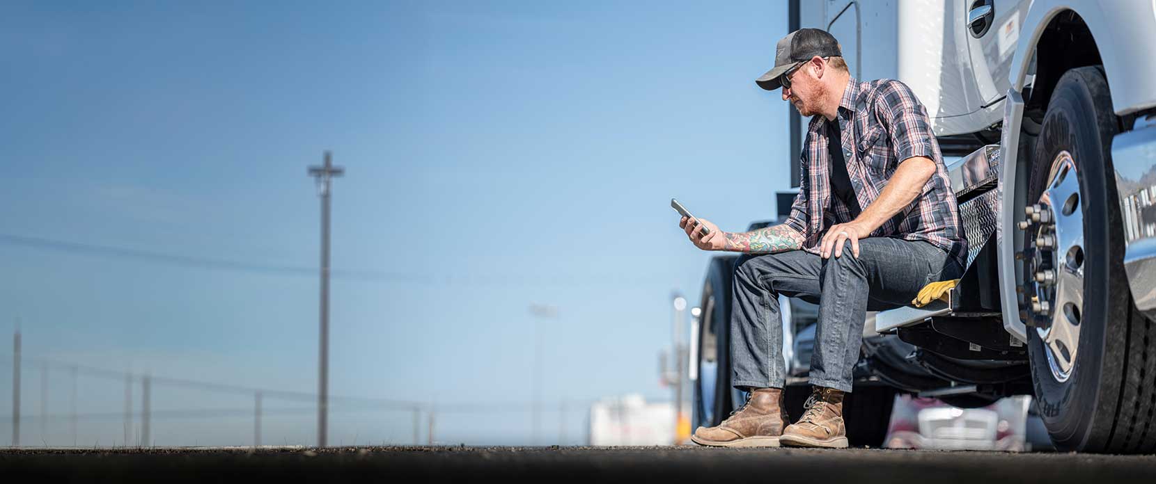 Truck driver checking phone beside truck